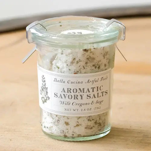 The BELLA CUCINA - WILD OREGANO & SAGE SALT is a small jar featuring a metal clasp and an herb-adorned label, blending European flat crystal salt with wild oregano and crushed sage leaves.