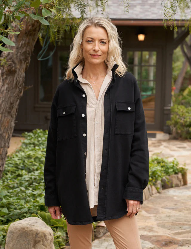 Presenting the Frank & Eileen McLoughlins Utility Jacket: a black, long-sleeve garment with a collared neckline and button-down front. It boasts two chest pockets with button closures and slightly rolled-up sleeves for a touch of California-cool. The label on the inside collar proudly displays "Frank & Eileen," set against a plain, textured white background.