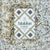 A box of GOURMET FOOD SOLUTIONS' MALDON - GARLIC SEA SALT is placed on a bed of coarse salt with herbs and garlic flakes scattered around. The box, in a green and white geometric design, reads "MALDON - GARLIC SEA SALT" and "with white & roasted garlic," established 1882—proudly showcasing its English sea salt heritage.