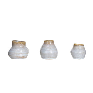 Three small TERRACOTTA GLAZED VASES by CREATIVE COOP, round with a smooth reactive glaze in white and light brown, are displayed in a row. Each piece varies slightly in shape and size, enhancing their unique handcrafted look.