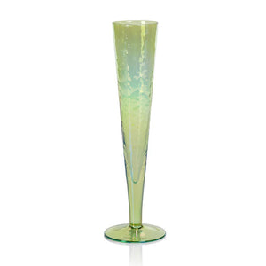 Introducing the APERITIVO SLIM CHAMPAGNE FLUTE - LUSTER GREEN by ZODAX, a tall and slender champagne flute with a captivating green iridescent finish and subtly textured surface. This exquisite piece boasts a narrow stem and gracefully tapered bowl that beautifully reflects light in shades of yellow and green, making it an exceptional choice for any celebration.