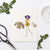 The KNIT AND PURL GREETING CARD by PETAL PEOPLE PRESS features an artful arrangement of vibrant dried flower petals, leaves, and stems on a pristine white background. A delicate skeleton leaf enhances its enchanting appeal, with the presence of tweezers and small scissors hinting at a whimsical crafting or botanical project.