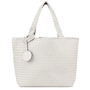 The WOVEN REVERSIBLE TOTE BAG by LINES OF DENMARK is a white tote featuring two shoulder straps and a circular faux-leather tag on one strap. This shopper showcases a textured, interlaced pattern and reversible design, providing stylish and elegant dual styling options. The image background is plain white.