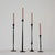 Four elegant CAST IRON TAPER HOLDER 24" by CREATIVE COOP cradle pink spiral candles in varying heights. Each hand-forged piece stands against a white backdrop on a light surface, showcasing exquisite craftsmanship.