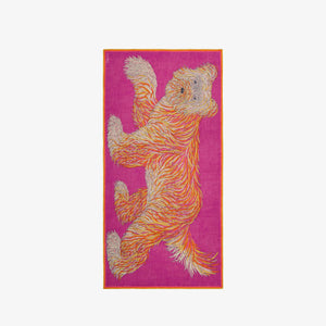 The INOUI EDITIONS - FREDDY SCARF from INOUI is a vibrant tapestry showcasing a distinctive design with an abstract bear against a lively pink backdrop. The bear is portrayed in dynamic shades of orange, yellow, and white, giving it a textured look, while the scarf's border contrasts elegantly in orange. Ideal as a summer accessory.