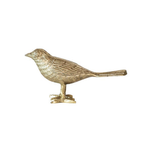 The CAST ALUMINUM BIRD by CREATIVE COOP is a small golden figurine of a bird, featuring detailed feather markings and standing on two legs. Crafted in cast aluminum with a smooth and shiny gold finish, the bird is facing left and perched on a small, flat base. It boasts an elongated tail and a pointed beak, making it an exquisite piece of bird decor.