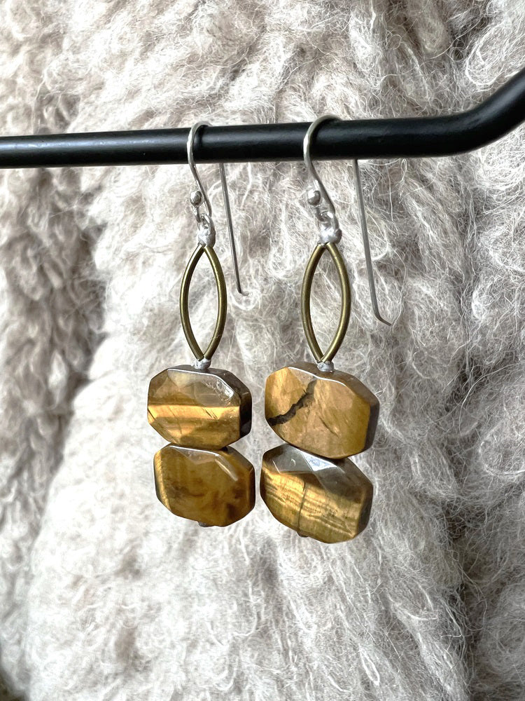 ANN LIGHTFOOT Tiger Eye Faceted Double Drop Rectangle Earrings feature gold and brown stones with brass connectors, hanging from sterling silver earwires. Shown on a soft, textured, light beige fabric background.