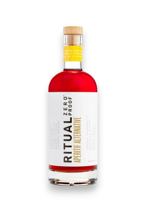 A tall, clear bottle with a yellow cap contains a red liquid. The label reads "RITUAL ZERO PROOF- APERITIF ALTERNATIVE" in large, modern font, along with additional small text detailing the product. The design is minimalistic, featuring white, yellow, and black colors.