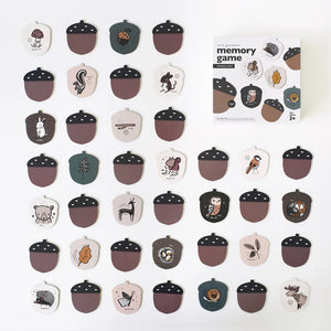 The WEE GALLERY - WOODLAND MEMORY GAME from WEE GALLERY is laid out on a white surface, showcasing pairs of cards with illustrations of birds, owls, snails, and rabbits. An open box also holds some additional cards, making it perfect for boosting cognitive skills.