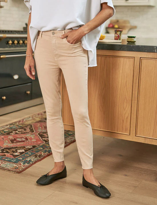The FRANK &amp; EILEEN SLIGO SKINNY JEAN is a pair of beige, high-waisted skinny jeans crafted from sustainable Italian Performance Denim. They feature a high-rise contour waistband, five pockets, button and zip closure, and a &quot;Frank&quot; label on the waistband. The jeans are displayed against a white textured background.