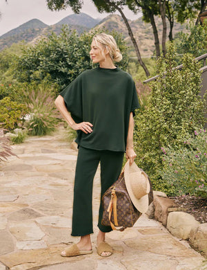 A pair of FRANK & EILEEN - CATHERINE FAVORITE SWEATPANT in dark green with wide legs and an adjustable drawstring waistband. These relaxed-fit sweatpants are crafted from a comfortable, soft fabric that feels reminiscent of Triple Fleece. They are laid flat against a light, textured background.