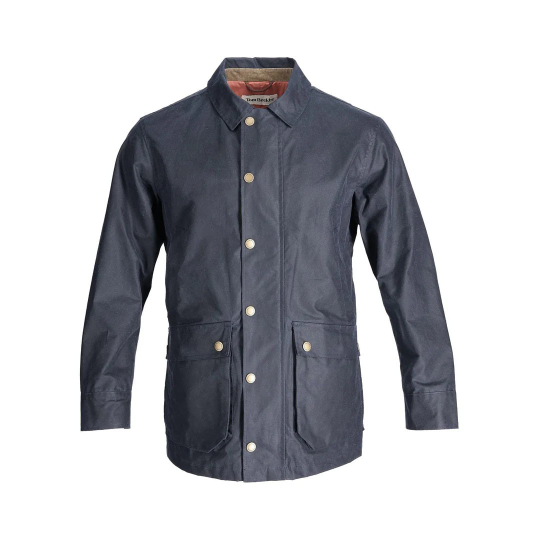 The TOM BECKBE Piedmont Jacket in Navy features waxed cotton, long sleeves, a collar, snap button closures, two large front pockets, and a contrasting interior lining. This weatherproof jacket combines classic style with durability.