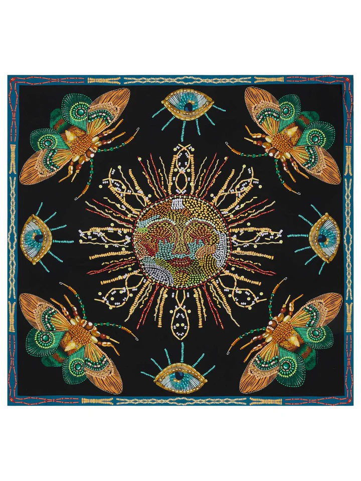 A black, intricately patterned silk 90x90 carré foulard from FRANCO FERRARI, designed with green and gold elements, folded into a triangle and tied with a knot, featuring a teal and red border and handrolled hem.