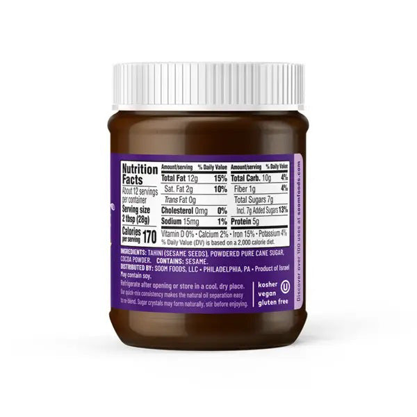 The SOOM FOODS - SOOM CHOCOLATE TAHINI comes in a brown jar with a white screw-on lid. The label displays nutrition facts, including serving size, calories, and amounts of total fat, cholesterol, sodium, carbohydrates, and protein. This chocolate spread is labeled kosher, vegan, and gluten-free.