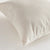 A close-up side view of the COOPER SQUARE INDOOR-OUTDOOR PILLOW 20" by NAPA HOME AND GARDEN against a plain, light background. The image showcases the pillow's white, textured Jacquard fabric and stitching detail, with the zipper partially visible on the edge.