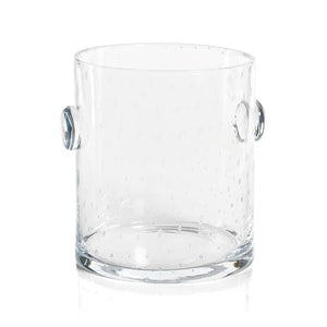 Product Description: The LAGOON BUBBLED ICE BUCKET by ZODAX is a clear, cylindrical glass vessel adorned with small, evenly distributed bubble-like textures. It features protruding circular handles on each side for easy handling. Designed with precise dimensions, the ice bucket boasts a smooth rim and a flat base.