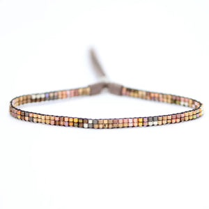 The JULIE ROFMAN - MINI BRACELET by JULIE ROFMAN JEWELRY is a vibrant handwoven piece adorned with small, square beads in various shades of pink, red, and white. It is displayed against a white background and includes a straightforward sterling silver clasp for convenient fastening.