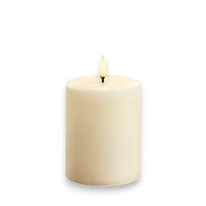 The PIFFANY UYUNI - IVORY PILLAR CANDLE 3X4 features a gentle flickering 3D flame atop a smooth, cylindrical wax surface and includes remote control functionality for tailored ambiance against a white background.