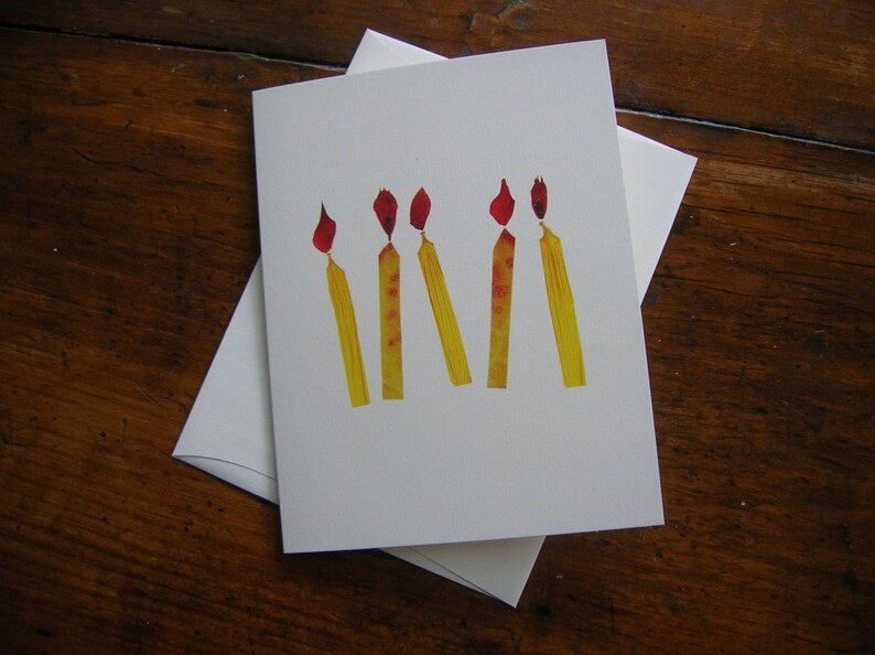 Five vibrant candle shapes in bright yellow with red flames stand out against a white background, resembling long, thin rectangles with pointed tops. This abstract and artistic design, featured on the CANDLES CARD by PETAL PEOPLE PRESS, evokes the delicate beauty of botanical art birthday cards.