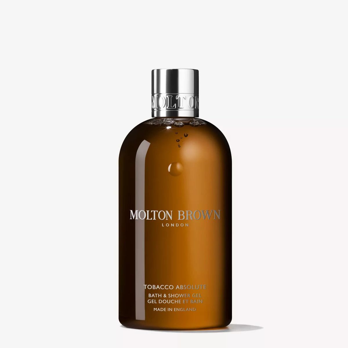 A 300ml brown bottle of MOLTON BROWN - ABSOLUTE TOBACCO BATH AND SHOWER GEL with a silver cap, featuring cedarwood notes, is displayed against a plain white background.