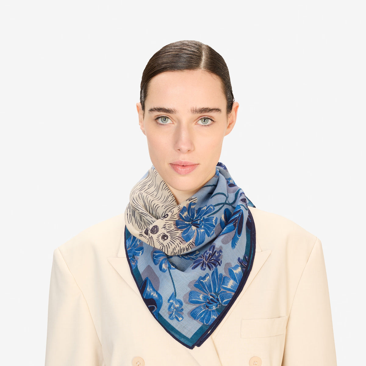 A close-up of the INOUI EDITIONS TOUTOU DOGGIE Wool Scarf in Blue shows its soft, woven texture and abstract blue, beige, and navy patterns. This 70x70cm INOUI accessory is gently twisted to highlight its intricate design—perfect for any wardrobe.