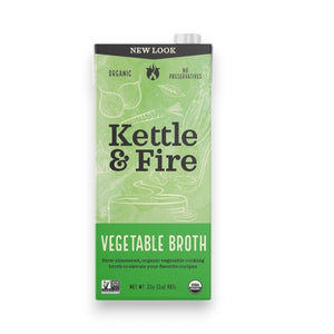 A carton of KETTLE & FIRE - ORGANIC VEGETABLE COOKING BROTH with a green label. The text highlights "Organic Ingredients" and "No Preservatives." The front features the product name and an illustration of vegetables. It states "New Look" at the top and specifies a net weight of 32 fl oz (907g), perfect for cooking flavorful meals.