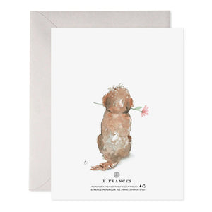 The DOG MOM MOTHERS DAY CARD by E.FRANCES PAPER is a handcrafted greeting card ideal for Mother's Day, showcasing a watercolor illustration of a fluffy dog with a pink flower in its mouth. A heart above the dog displays "Happy Mother's Day," and an envelope accompanies it.