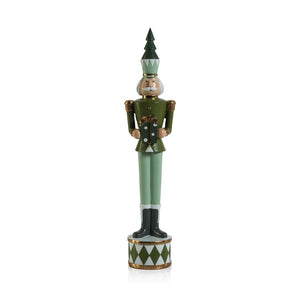 Two decorative ZODAX Nutcracker Soldiers with Gift Boxes stand on a metallic tray. Each figure wears a tall hat and a uniform in shades of green, adorned with intricate details. The product description emphasizes the neutral-toned background, which allows these festive figures to stand out in the foreground.