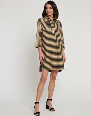 A woman stands posing sideways in a knee-length, loose-fitting HINSON WU AILEEN 3/4 Sleeve Dress featuring a classic black and tan stripe and gingham combo. She has shoulder-length dark hair and wears black high-heeled sandals. The background is a plain white wall.