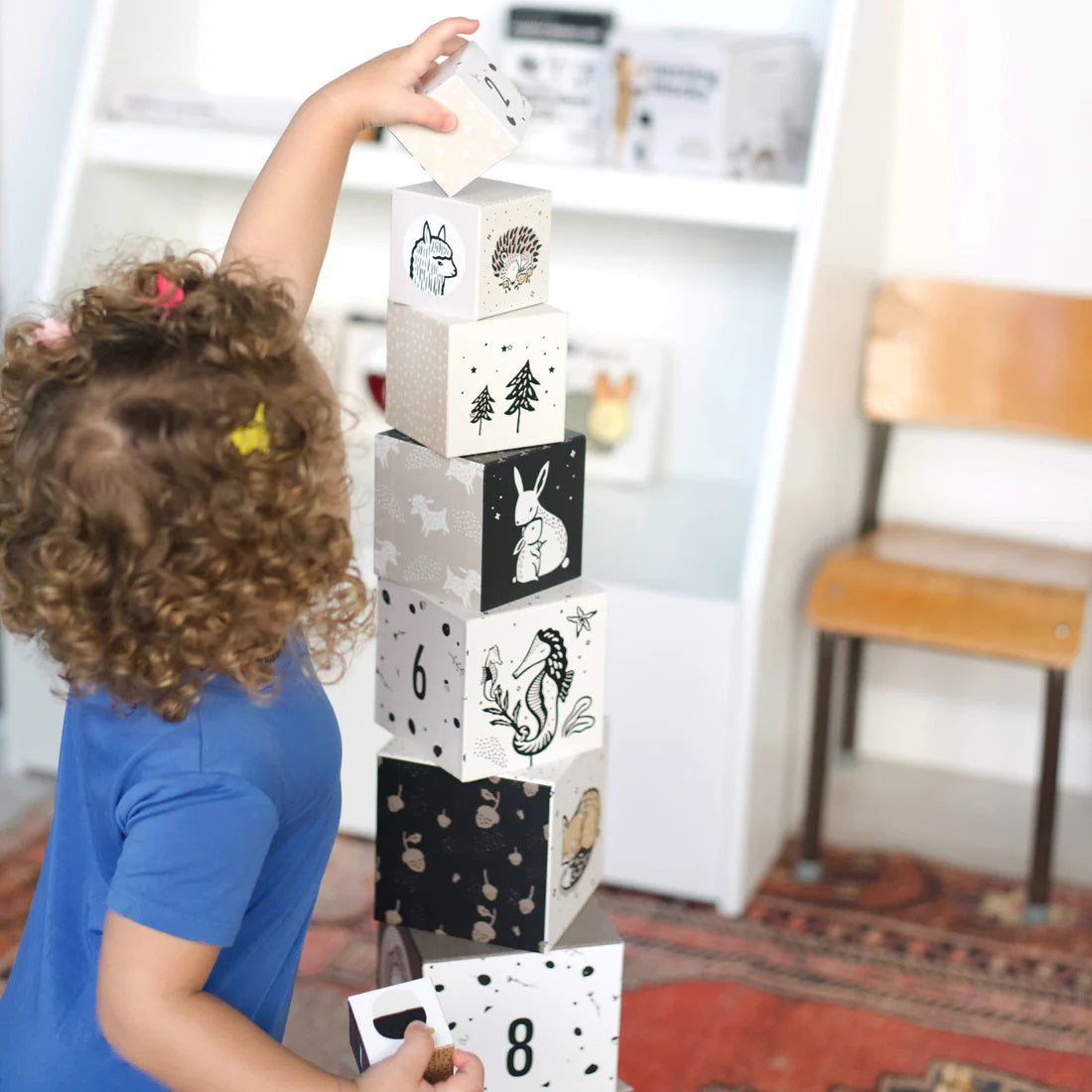 The WEE GALLERY - BABY ANIMAL NESTING BLOCKS, featuring monochrome animal illustrations and numbers, are perfect for developing early math concepts. The left stack includes woodland animals, while the right stack displays numbers 5, 6, and 7 adorned with more animal images. These nesting blocks from WEE GALLERY also help enhance motor skills against a plain white background.