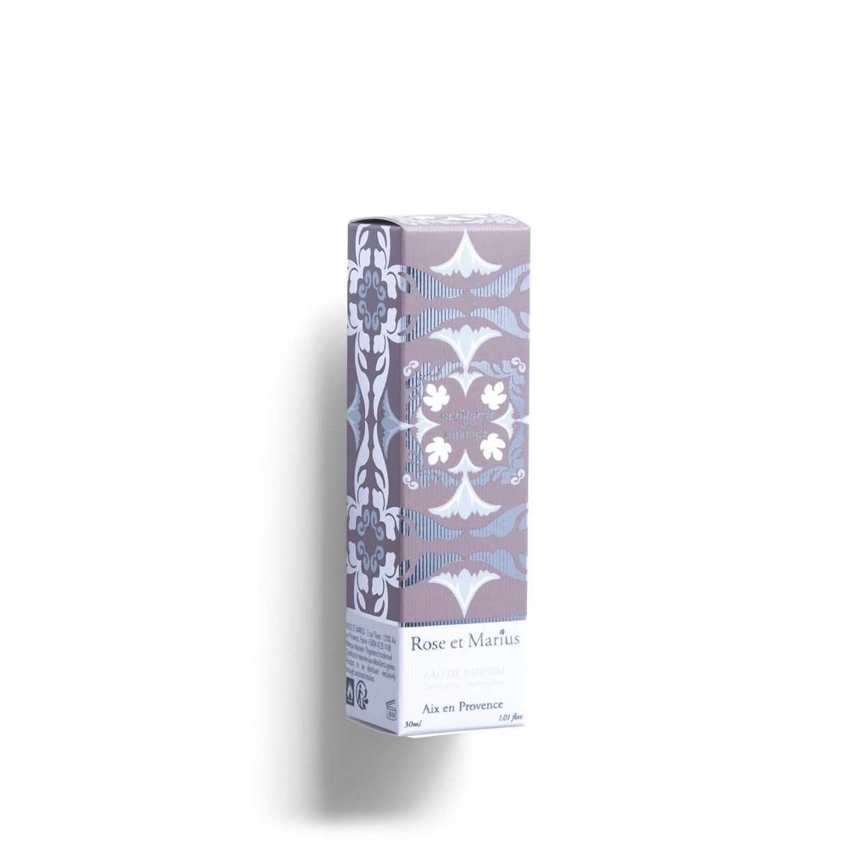 A tall, clear glass bottle of ROSE ET MARIUS’s A Stroll Under the Oratory Eau de Parfum 30ml, unisex with a light golden liquid and decorative floral-patterned square cap, is placed to the side on a white background.