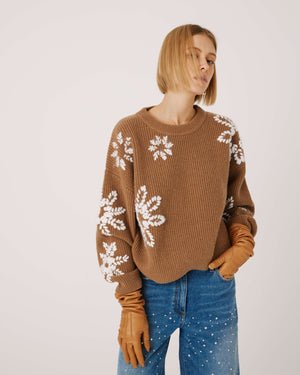 The SFIZIO - WOOL BLEND CREWNECK SWEATER WITH HAND EMBROIDERED FLOWERS by SFIZIO is a brown wool blend sweater featuring white snowflake patterns on the sleeves and chest. Crafted with an English rib knit, it has a ribbed texture and a crew neck.