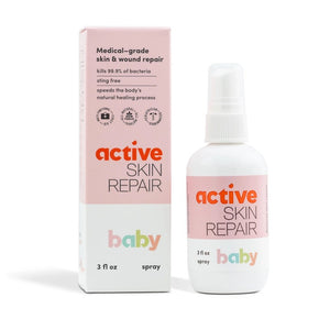 A white bottle of ACTIVE SKIN REPAIR - BABY SPRAY ACTIVE SKIN REPAIR, shown from the back, displays text and icons indicating usage instructions and ingredients. The bottle features a white spray nozzle on top and a barcode at the bottom. Ideal for diaper rash and skin irritations, it mentions no harsh chemicals or added fragrances.