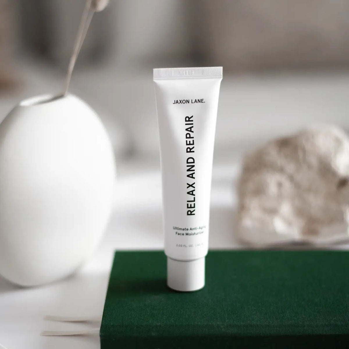 A white tube labeled &quot;JAXON LANE - RELAX AND REPAIR ANTI AGING FACE MOISTURIZER&quot; stands beside a matching black box. This fragrance-free men&#39;s moisturizer from JAXON LANE contains 2.03 fl. oz. (60 ml) of product.