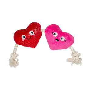 The PET SHOP BY FRINGE STUDIO's "CAN'T BE AP-HEART DOG TOY" features two plush, heart-shaped squeakers in red and pink with cute faces and sparkly textures, connected by a knotted white rope, perfect for dogs of all sizes.