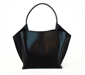 Introducing the RIGID LEATHER HANDBAG by LEATHER COUNTRY, a stylish black handbag with a unique geometric shape, featuring a top handle and a removable shoulder strap. The bag boasts gold-tone hardware, a magnetic closure, and an unlined interior spacious enough for your daily essentials.