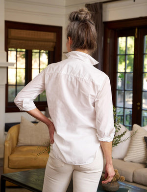 A FRANK AND EILEEN - FRANK CLASSIC BUTTON-UP SHIRT SUPERFINE POPLIN in white, featuring a classically tailored long-sleeve design with rolled-up sleeves, is displayed against a plain, textured background. The label inside the collar reads "FRANK & EILEEN." This shirt offers a classic, slightly relaxed fit with a curved hemline and bust-flattering button placement.