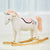 The WONDER AND WISE ASWEETS UNICORN ROCKER features a white fabric unicorn with a unicorn horn, light pink mane and tail, and a light pink saddle. Mounted on a wooden rocker base, it includes magical details such as stitched eyes and a small side pocket for added comfort.