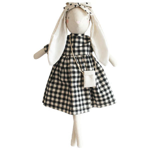 The ALIMROSE - SOFIA BUNNY BLACK CHECK is a handcrafted, ethically stuffed doll from ALIMROSE. It wears a black and white gingham dress with a matching fabric headband that accentuates its long ears, and it carries a small bag around its neck. This charming bunny, made from the finest materials, features simple stitched facial details.