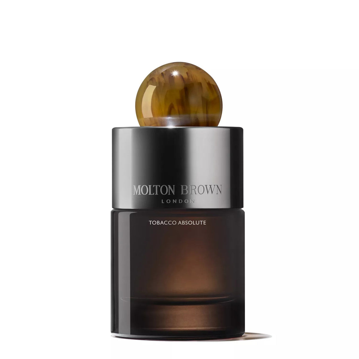 A 100ml bottle of MOLTON BROWN - TOBACCO ABSOLUTE EAU DE PARFUM, featuring a dark glass body, metallic cap, and round amber top, is displayed against a white background to reflect the woody fragrance&#39;s essence.