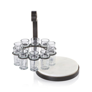 The ZODAX TEQUILERO 10 Shot Tequila Set with Marble Cutting Board is displayed on a table, featuring tequila bottles, lemon wedges, and clear iron-trimmed shot glasses against a dark textured background.