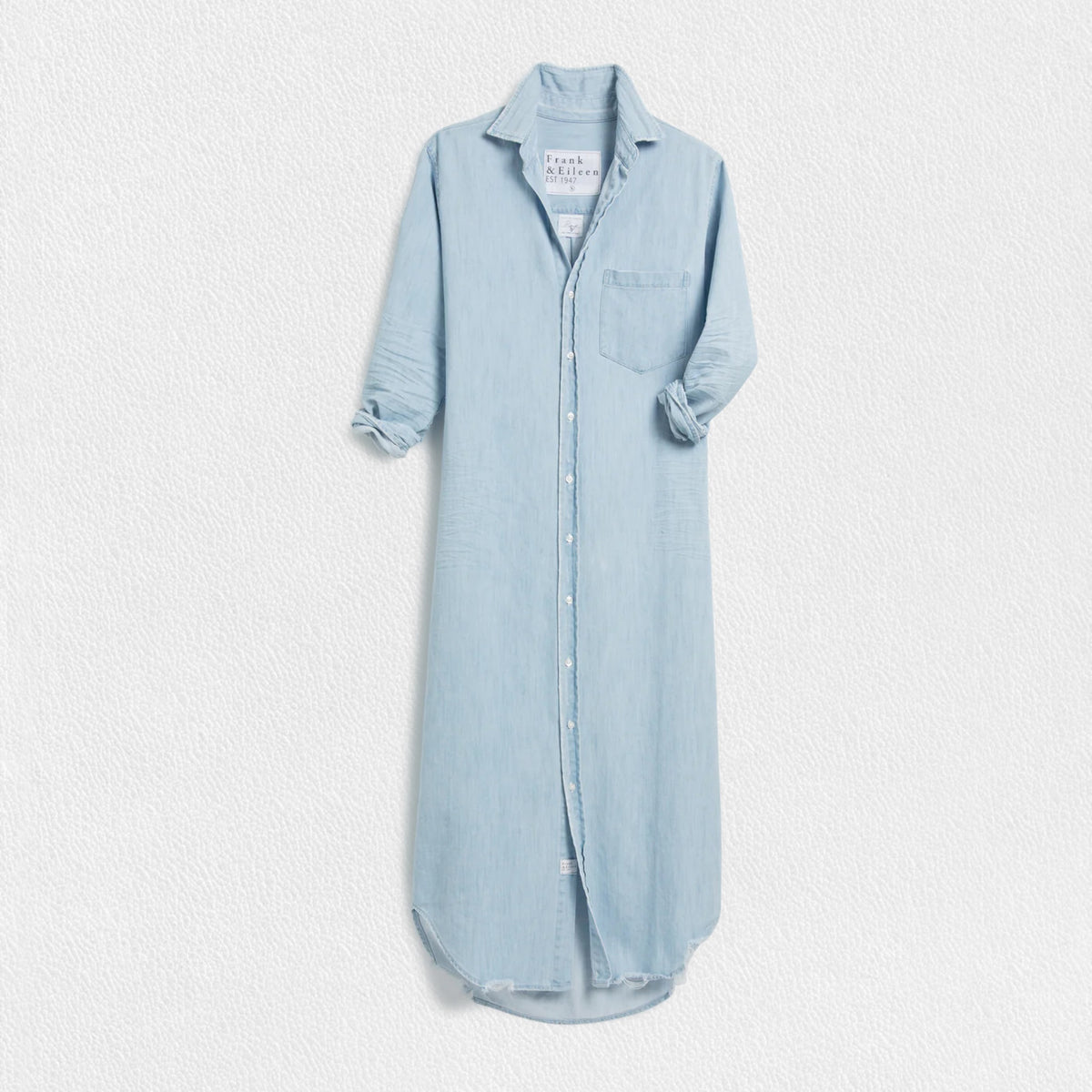 The FRANK &amp; EILEEN Rory Maxi Shirtdress in Famous Denim is a full-length button-up dress featuring a collar, rolled-up sleeves to mid-length, and a single chest pocket. Its sleek, minimalist design embodies that California chic look against a plain white textured background.