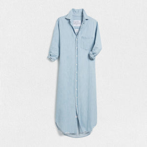 The FRANK & EILEEN Rory Maxi Shirtdress in Famous Denim is a full-length button-up dress featuring a collar, rolled-up sleeves to mid-length, and a single chest pocket. Its sleek, minimalist design embodies that California chic look against a plain white textured background.