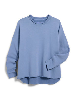 The FRANK & EILEEN ANNA Long Sleeve Capelet in Blueberry is showcased against a plain white background. This light blue, long-sleeve, crew-neck shirt boasts a relaxed fit and seamless hem, crafted from soft Triple Fleece. The slightly oversized design features the left sleeve casually folded at the cuff.