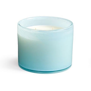 A serene setup with a LAFCO Marine Bathroom 3 Wick Candle and a smaller soy candle, both lit, beside a blue reed diffuser. The soft blue background evokes a calming sea air atmosphere.