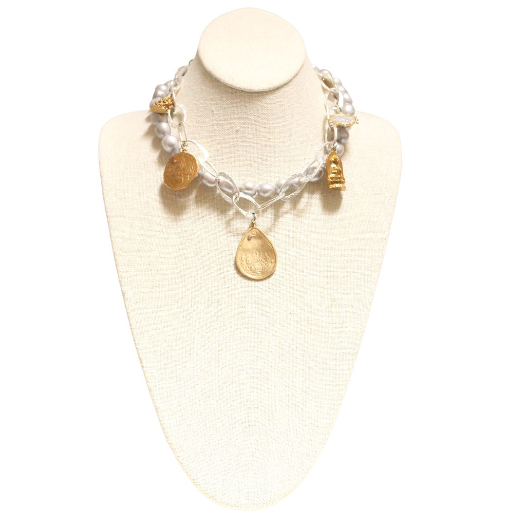 A BITTERSWEET DESIGNS - MIXED BLESSINGS SILVER AND PEARL NECKLACE displayed on a white mannequin bust. Handmade by artisans, it features a mix of clear beads, gold charms, and white pearls. The charms include gold shapes like hearts and leaves, adding a decorative touch to the elegant design.