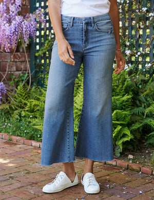 The FRANK & EILEEN Galway Gaucho Jean in the 1972 Wash offers a high-waisted, wide-leg design with a subtle faded effect and classic five-pocket styling, perfectly embodying the spirit of Italian Dream Denim. Featuring a raw hem for that iconic gaucho-style, these light blue jeans are showcased against a lightly textured background.