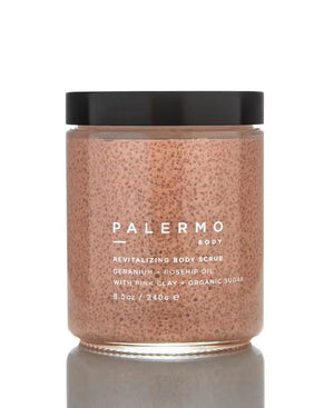 The PALERMO BODY GERANIUM AND ROSE HIP BODY SCRUB comes in a clear jar with a black lid. This pink scrub, rich in French pink clay and organic sugar granules, offers revitalizing benefits. The label lists ingredients such as geranium, rosehip oil, and organic sugar. This 8.5 oz / 240 g jar also features aromatherapeutic properties.
