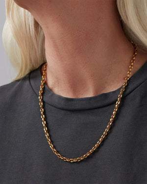 The JENNYBIRD dhani chain necklace is a delicate 14K gold-plated piece with interlinked circular links. It rests against a light neutral background, showcasing its elegant design and durable stainless steel construction.