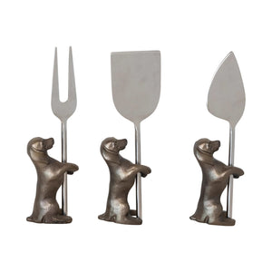 The CREATIVE COOP set, CHEESE KNIVES WITH DOG STAND, includes three silver utensils perfect for cheese: a fork, flat blade, and pointed blade. Each features an intricately detailed metallic dog-shaped handle, making them ideal companions for your serving tray.